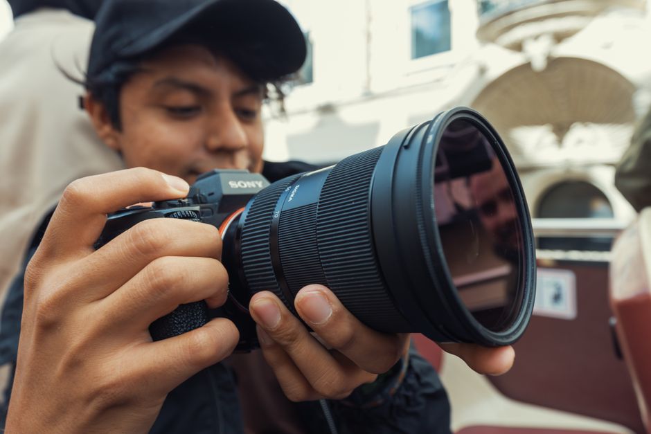 Young photographer adjusting camera settings while capturing outdoor scenes.